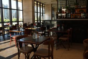 un restaurante con mesas, sillas y ventanas en Flat Premium Particular Cullinan Hotel, en Brasilia