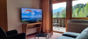 a living room with a flat screen tv and a balcony at Berghof Mehlan in Fischen
