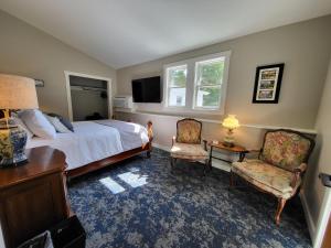 a bedroom with a bed and two chairs and a television at The Stowe Village Inn in Stowe