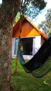a hammock hanging from a tree in front of a house at Casa Kafka - Bio Cult in Campo Alegre
