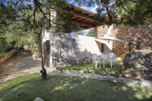 un jardín con mesa y sombrilla en MaryLou by DomusAway, en Monte Petrosu