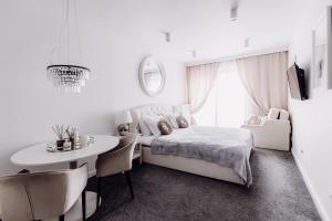 ein weißes Schlafzimmer mit einem Bett und einem Tisch in der Unterkunft APARTAMENTY ARTE LUBLIN Boczna Lubomelskiej 11 garaż in Lublin