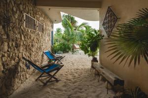 Casa Mia El Cuyo Eco Beach Boutique Hotel في إل كويو: بضعة كراسي جالسة على الرمال بجوار مبنى