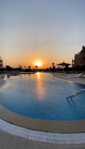 een groot zwembad met een zonsondergang op de achtergrond bij la hacienda in Ras Sedr