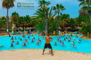 un homme debout en face d'une piscine d'un complexe dans l'établissement Welcome Meridiana Resort - Families and Couples Only, à Djerba