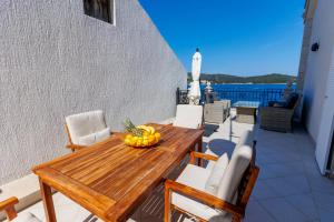 a wooden table on a balcony with a bowl of fruit at Seafront Apartment For4 in Vis