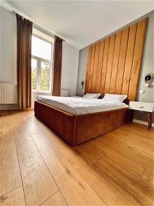 a bedroom with a large bed with a wooden headboard at LV Luxury Apart - One minute away from train station in Predeal