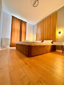 ein Schlafzimmer mit einem großen Bett und Holzboden in der Unterkunft LV Luxury Apart - One minute away from train station in Predeal