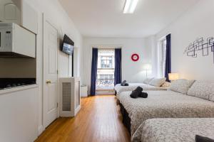 um quarto branco com 2 camas e um sofá em Studio Plus - Cozy Apartments em Nova York
