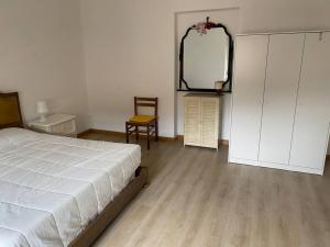 ein Schlafzimmer mit einem Bett, einem Spiegel und einem Stuhl in der Unterkunft Appartamento a Monfalcone, con parcheggio gratuito in Monfalcone