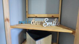 una mensola di legno con un cartello che dice "nuovo sorriso da droghe" di Jimmy's place a Artemida