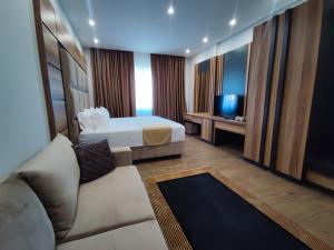 Cette chambre comprend un lit, un canapé et une télévision. dans l'établissement Hilal Palace - Halal, à Golem