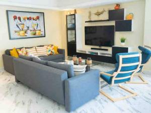 a living room with a couch and chairs and a television at Exclusive brand new 3BR condo at Cap Cana in Punta Cana