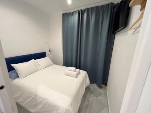 um pequeno quarto com uma cama branca e cortinas azuis em MonKeys Apartments Santa Clara Deluxe em Sevilha