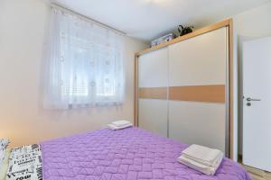 sypialnia z fioletowym łóżkiem i szafą w obiekcie Apartment South w mieście Zadar