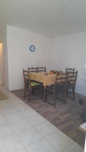 a dining room with a table with chairs and a clock on the wall at Kućerak in Irig