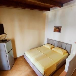 Mejdi Apartments في سارنده: غرفة نوم بسرير وثلاجة صغيرة