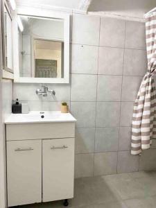ein Bad mit einem Waschbecken und einem Spiegel in der Unterkunft Прекрасная квартира на берегу Средиземного моря in Qiryat H̱ayyim