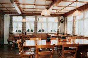 ein Restaurant mit Holztischen, Stühlen und Fenstern in der Unterkunft Hotel Krone Gais in Gais