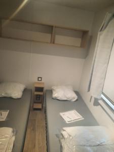 a small room with two beds and a window at Mobil-home premium 325 in Narbonne