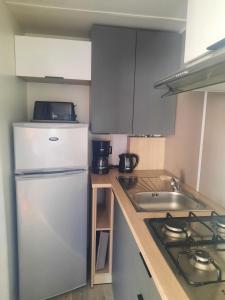 La cuisine est équipée d'un réfrigérateur blanc et d'un évier. dans l'établissement Mobil-home premium 325, à Narbonne