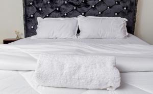 Cama blanca con cabecero negro y almohadas blancas en Sparkle Homes 