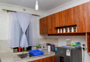kuchnia z drewnianymi szafkami, zlewem i lodówką w obiekcie Sparkle Homes 