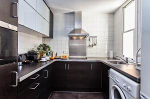 バルセロナにあるSweet Inn - Dali Apartment Graciaのキッチン(黒いキャビネット、シンク付)
