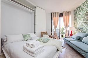 - une chambre avec un lit blanc et un canapé dans l'établissement Sweet Inn - Cosy Ciutadella, à Barcelone
