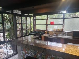 eine Küche mit einer Theke mit einer Spüle und Fenstern in der Unterkunft Chalés internacional l in Paraty