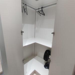 a walk in closet with white walls and shelves at La Home House6 - Apto Studio Completinho com elevador em SJP - 10 minutos Aeroporto Afonso Pena - Curitiba in São José dos Pinhais