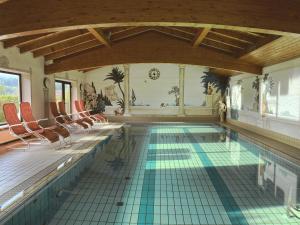 an indoor swimming pool with chairs and a tile floor at Hotel Sonnenhof - Superior in Zwiesel