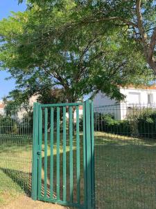 een groene poort voor een hek met een boom bij Charmant studio in La Rochelle