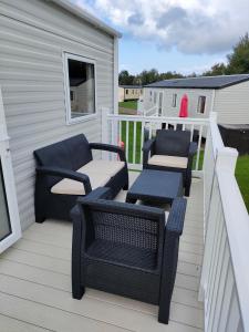 eine Terrasse mit zwei Stühlen und einer Bank auf einem Haus in der Unterkunft 3 Bedroom Stylish Caravan - Vans With Business Sign Not Allowed in Port Seton