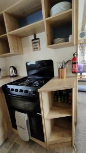 a kitchen with a black stove and a wooden cabinet at 3 Bedroom Stylish Caravan - Vans With Business Sign Not Allowed in Port Seton