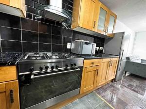 a kitchen with a stove top oven in a kitchen at NEW! 4 Bedroom London House with Garden and Lawn in London