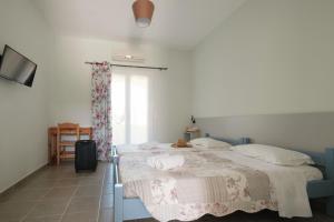 a bedroom with a bed with white sheets and a window at Feeloxenia Corfu Apartments in Acharavi