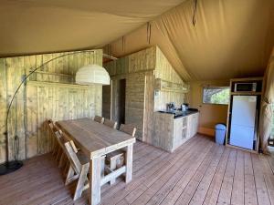 une salle à manger avec une table en bois dans une tente dans l'établissement Lodges du Bois Dodo - ancien Camping de Bois Redon, à Septfonds