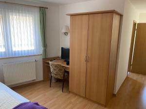 a bedroom with a desk with a computer and a cabinet at Hotel-Restaurant Theis-Muehle in Biersdorf