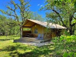 une tente avec deux chaises et une table dans un champ dans l'établissement Lodges du Bois Dodo - ancien Camping de Bois Redon, à Septfonds
