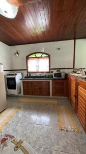 a large kitchen with wooden cabinets and a window at Casa Ipê in Monte Verde