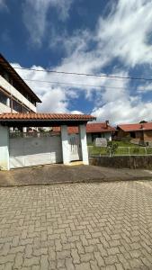 a white building with a red roof on a brick road at Casa Ipê in Monte Verde