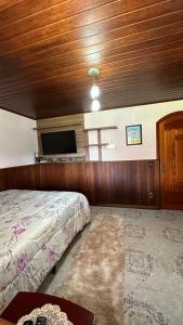 a bedroom with a bed and a flat screen tv at Casa Ipê in Monte Verde