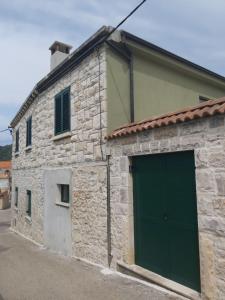 un edificio de piedra con una puerta de garaje verde en Villa Gitta en Vela Luka