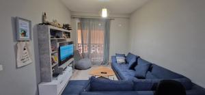 uma sala de estar com um sofá azul e uma televisão em Cozy apartament in Tirana em Tirana