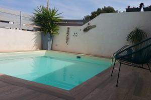 a swimming pool with a chair next to a wall at Maison 4/6 pers avec piscine proche des plages in Sausset-les-Pins