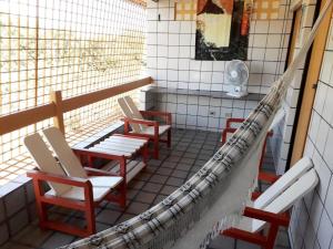 uma varanda com cadeiras e uma ventoinha num quarto em Flat260 Beira Mangue Mar ar piscinas estac zelador em Itamaracá