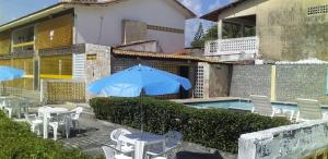 uma piscina com mesas e cadeiras e um guarda-sol em Flat260 Beira Mangue Mar ar piscinas estac zelador em Itamaracá