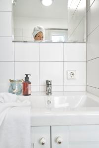 una persona que toma una foto de un lavabo de baño en SEEMOMENTE Überlingen an der Promenade, en Überlingen