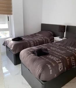 dwa łóżka z brązowymi kołdrami w pokoju w obiekcie Modern penthouse with sea view w mieście Punta Prima